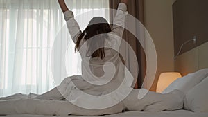 Woman wakes up in morning stretching arms in hotel room