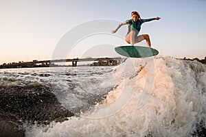 woman wakesurfer skilfully jumping on wakesurf over great splashing river wave photo