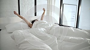 Woman Waking Up In Bed In Light Bedroom