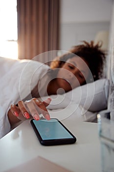 Woman Waking Up In Bed Reaches Out To Turn Off Alarm On Mobile Phone
