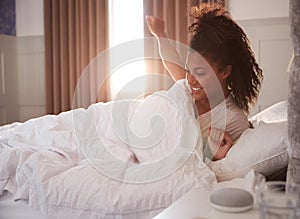 Woman Waking Up In Bed With Voice Assistant On Bedside Table Next To Her photo