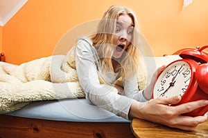 Woman waking up late turning off alarm clock.