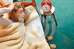 Woman waking up late turning off alarm clock.