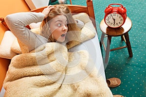 Woman waking up late turning off alarm clock.