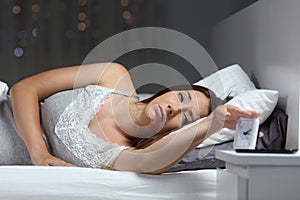 Woman waking up in the night turning off alarm clock