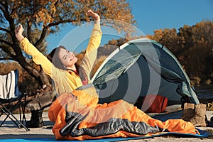 Woman waking up in sleeping bag near tent