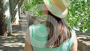 Woman walk along waterfront in slow motion. Behind view of female traveler enjoying vacation outdoor