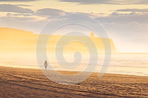 Woman walk on golden sand beach of portstewart strand by with castlerock lighthouse backgorund. Wild coast of northern ireland