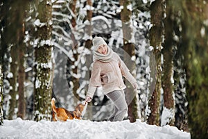 A woman on a walk with her dog in the winter forest. mistress and dog game in the snowy forest