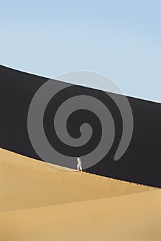 Woman walking across desert sand dunes