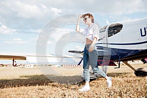 Woman walking across the field with plane on the background