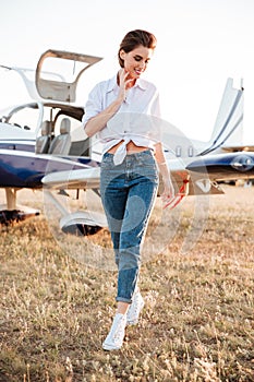 Woman walking across the field with plane on the background