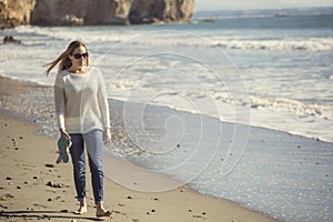 Woman walking alone along a peaceful beach thinking and pondering