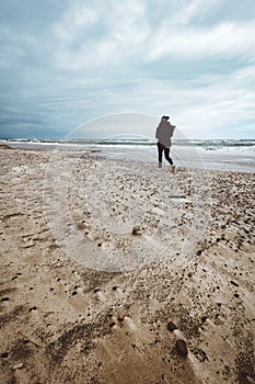 Woman walking alone on the beach on windy stormy day