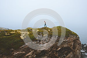 Woman walking alone on cliff rock travel lifestyle adventure vacations outdoor isolation solitude concept