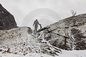 Woman walking alone, climbing a mountain in snowy weather.