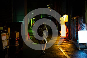 A woman is walking alone at the night street in the rainy season