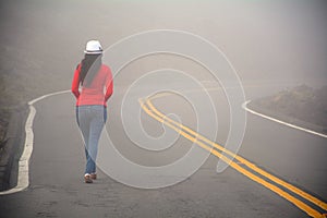 Woman walking alone on the road in the fog