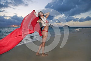 Woman walking along a beach at sunrise