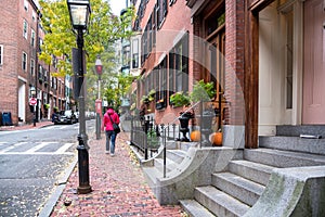 Woman walking along a brick pavement in a residential district on a cloudy autumn day