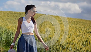 Woman is walking along the road among the fields