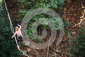 A woman is walking along a stretched sling over a forest