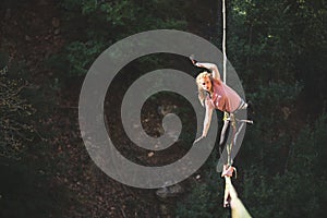 A woman is walking along a stretched sling over a forest