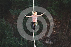 A woman is walking along a stretched sling over a forest, Purposeful girl goes to the goal