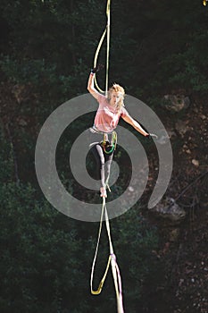 A woman is walking along a stretched sling over a forest, Purposeful girl goes to the goal