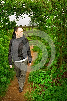 Woman walking through arch in hedge in countryside