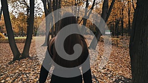 Woman Walking through Autumn Forest. . Girl in black coat and enjoying fall day outdoors, walking through woodland.