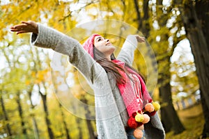 Woman walking in autumn park. rise her hands up.