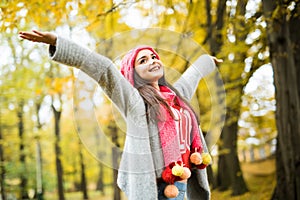 Woman walking in autumn park. rise her hands up.