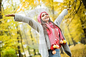 Woman walking in autumn park. rise her hands up.