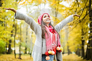 Woman walking in autumn park. rise her hands up.