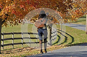 Woman Walking Away with Guitar in the Fall