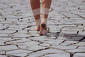 Woman walking barefoot across cracked earth