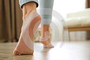 Woman walking barefoot at home, space for text. Floor heating concept