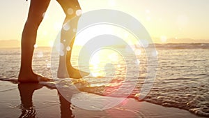 Woman walking barefoot in ocean on the sand against sunshine on ocean