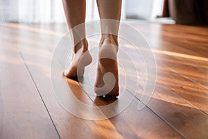 Woman walking barefoot on toes at warm floor closeup view