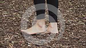 A woman walking barefoot on tree bark floor at the forest