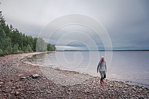 Woman walking at beach and lakeshore at Lake Siljan in Dalarna, Sweden photo