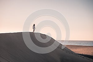 Woman walking at the beach of Maspalomas Gran Canaria Spain, girl at the sand dunes desert of Maspalomas