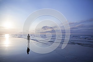 Woman walking on beach at sunrise