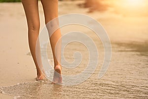 Woman walking on a beach with sunset