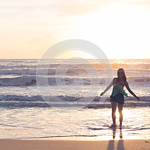 Woman walking on the beach, sunshine in the morning