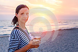 Woman walking on the beach in the surf at sunset