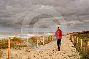 A woman walking on a beautiful sandy trail along the ocean. North Holland dune reserve, Egmond aan Zee, Netherlands