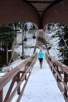 Woman walking on bridge over the frozen river.