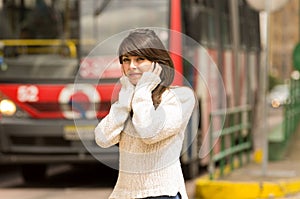 Woman walking on the city street covering her ears